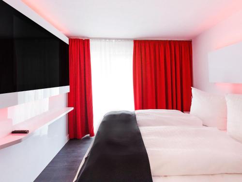 a bedroom with a bed and a red curtain at DORMERO Hotel Villingen-Schwenningen in Villingen-Schwenningen