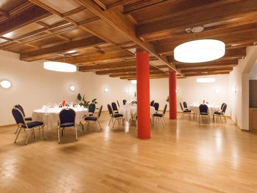 a large room with tables and chairs and red columns at DORMERO Hotel Villingen-Schwenningen in Villingen-Schwenningen