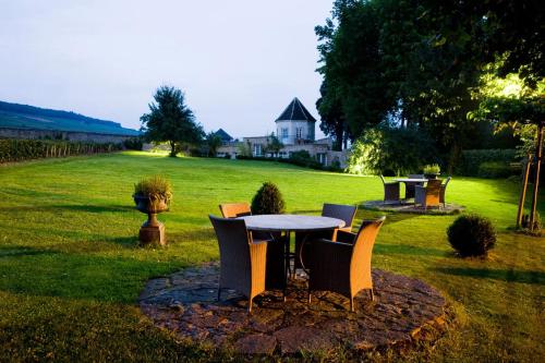 a table and chairs in a yard with a field at Villa Louise in Aloxe-Corton
