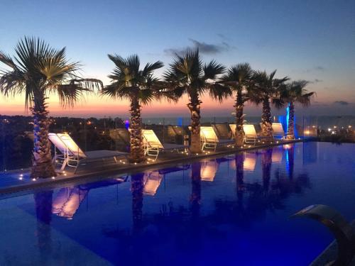 a pool with chairs and palm trees at night at Hugo's Boutique Hotel - Adults Only in St. Julianʼs