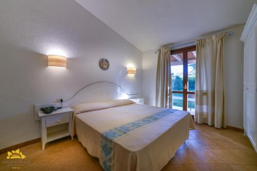 a bedroom with a large bed and a window at Hotel Garden Beach in Castiadas
