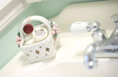 a white bathroom sink with a basket with fruit in it at Anne's White Columns Inn in Bar Harbor