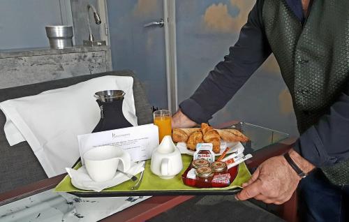 un homme tenant un plateau avec de la nourriture pour le petit-déjeuner dans l'établissement Apostrophe Hôtel, à Paris