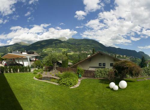 a yard with a house and mountains in the background at Residence Mignon in Rifiano