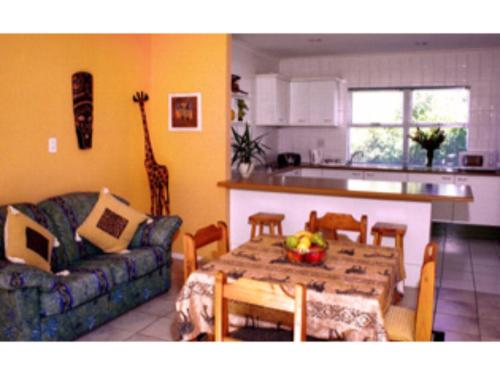 een keuken en een woonkamer met een tafel en een bank bij Blue Mountain Guest House in Bloubergstrand