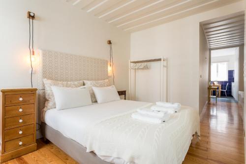 リスボンにあるFLH Bairro Alto Central Apartmentのウッドフロアのベッドルーム1室(白いベッド1台付)