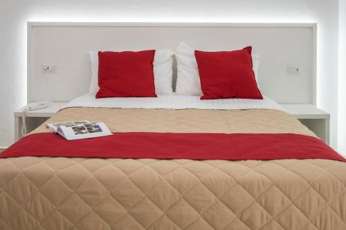 Una cama con almohadas rojas y un libro. en Palazzo Della Mura, en Angri