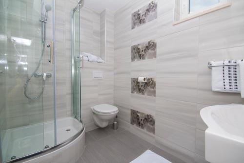een witte badkamer met een douche en een toilet bij Sea View Apartment Gin Brela in Brela