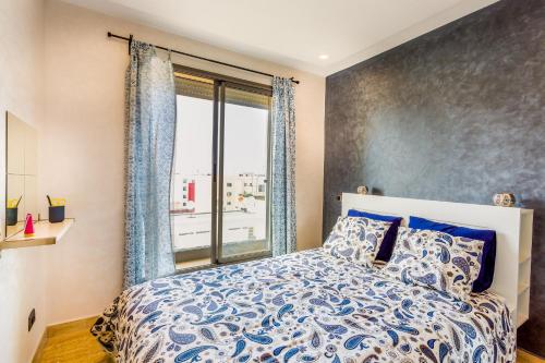 a bedroom with a bed and a large window at Appartement Mogador CASABLANCA in Casablanca