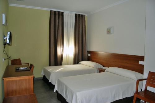 a hotel room with two beds and a window at Hotel Gema in Almadén