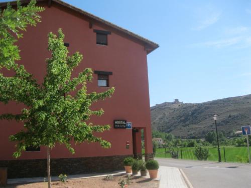 a red building with a tree in front of it at Hostal Sol de la Vega in Albarracín