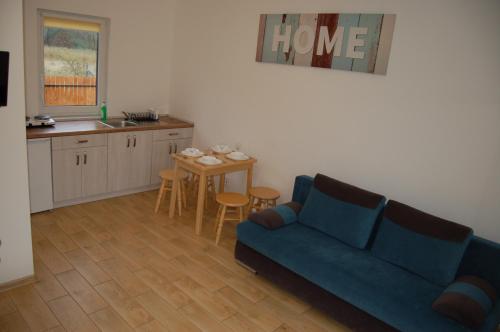 a living room with a blue couch and a kitchen at Dom nad morzem Sosenka in Mielenko