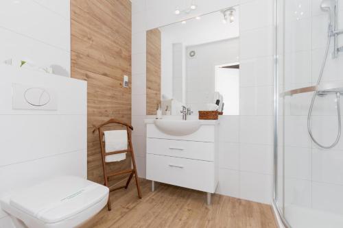a white bathroom with a shower and a sink at Grace Apartment II in Kołobrzeg