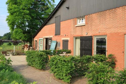 a red brick building with a horse in the background at Erfgoed & Logies Den Heijkant in Moergestel