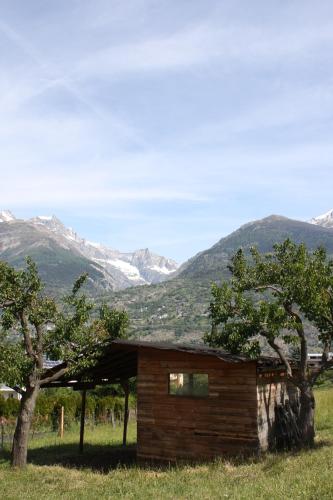 a log cabin in a field with mountains in the background at Hotel & Bildungshaus St. Jodern in Visp