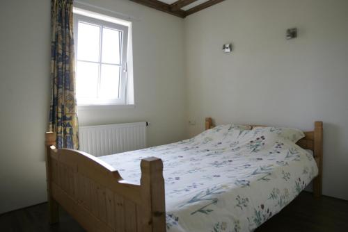 - un lit dans une chambre avec fenêtre dans l'établissement Vakantiehuis NamaStee, à Schoonloo