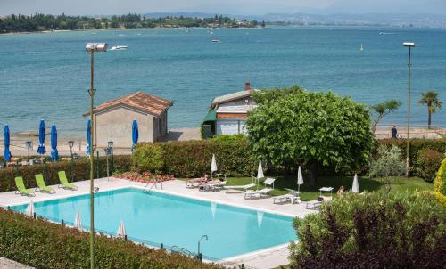 a swimming pool next to the ocean with chairs and umbrellas at Hotel Ristorante Al Fiore in Peschiera del Garda