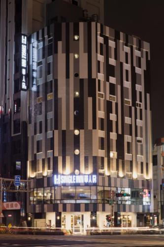 a large building with a sign on it at night at Single Inn-Kaohsiung Station in Kaohsiung