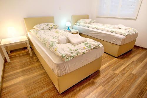 two beds in a room with wooden floors at Apartment Vita near Terme Paradiso in Dobova