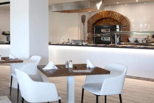 a restaurant with a table and chairs and a kitchen at Sandos El Greco - Adults Only in Portinatx