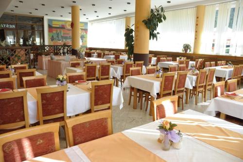 un comedor con mesas, sillas y mesas blancas en Hotel Magura, en Ždiar