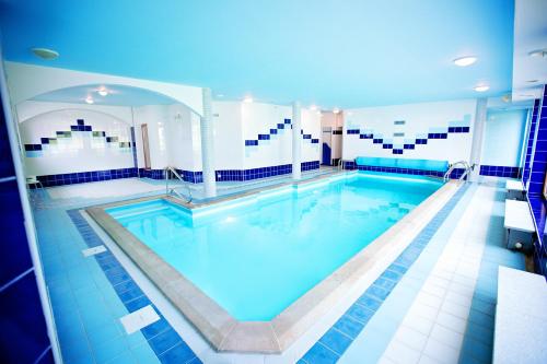 - une grande piscine revêtue de carrelage bleu et blanc dans l'établissement Hotel U Loubů, à Fryšava