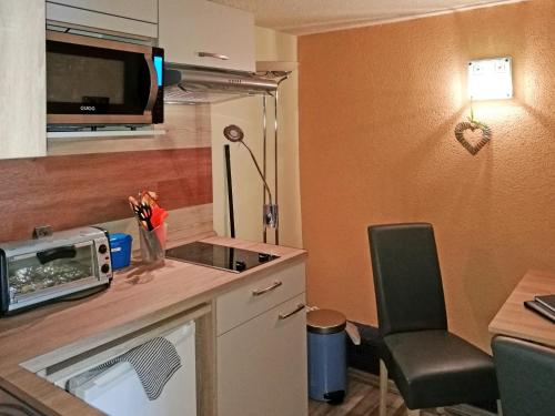 a small kitchen with a microwave and a table with a chair at Ferienwohnung Jan in Prohn