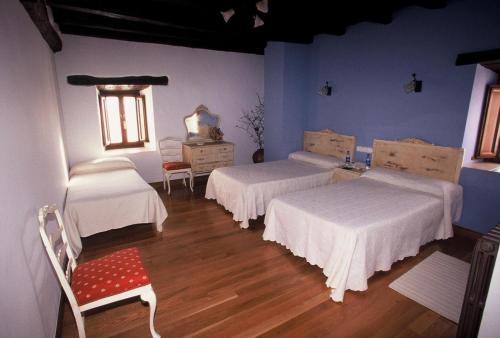 una habitación con 3 camas y una silla. en Casa Rural Bentazar, en Elosu