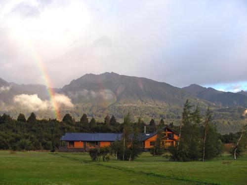 un arco iris sobre una casa frente a una montaña en Hosteria Ruca Kitai en Villa Lago Rivadavia