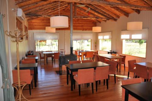 a dining room with tables and chairs and a stove at Hosteria Ruca Kitai in Villa Lago Rivadavia
