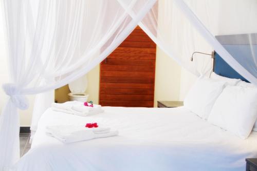 a bedroom with a white bed with two white slippers at Bilene Lodge by Dream Resorts in Vila Praia Do Bilene
