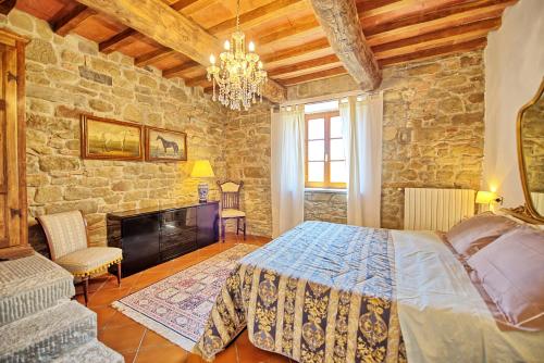 1 dormitorio con cama y pared de piedra en Villa Panzalla by PosarelliVillas, en Santo Stefano A Tizzano