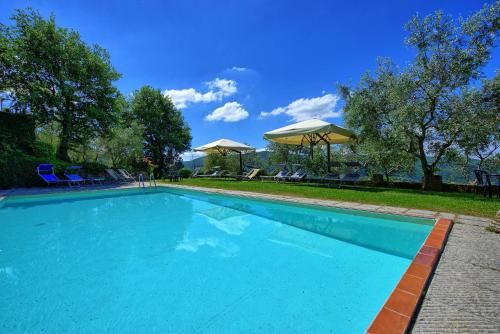 una gran piscina azul con sillas y sombrillas en Villa Panzalla by PosarelliVillas, en Santo Stefano A Tizzano