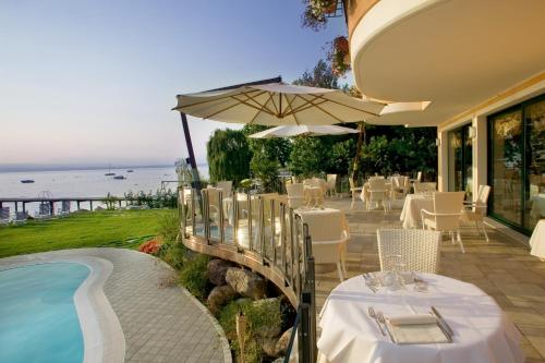 a patio with tables and an umbrella next to a pool at Hotel La Rondine in Sirmione