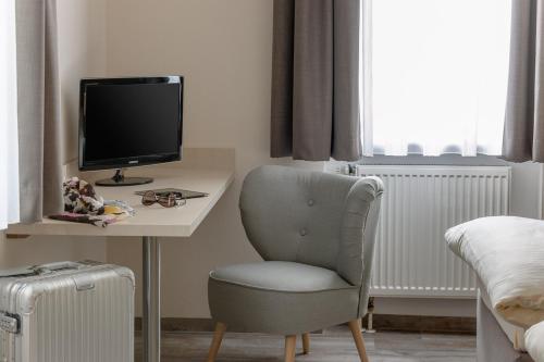 a bedroom with a desk with a chair and a television at sleepIN in Ingolstadt