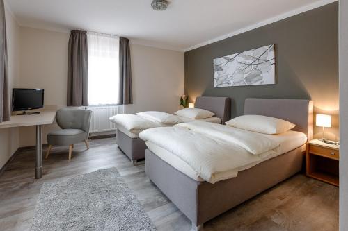 1 dormitorio con 4 camas, escritorio y TV en sleepIN, en Ingolstadt
