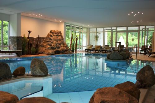 une grande piscine avec des rochers dans un hôtel dans l'établissement Waldhotel Bad Sulzburg, à Sulzburg