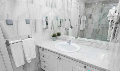 a white bathroom with a sink and a mirror at First Flatotel International in Benalmádena