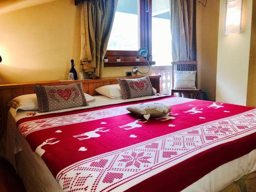 a bedroom with a large bed with a red and white blanket at Shatush Hotel in Courmayeur