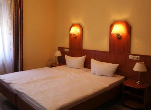 ein Schlafzimmer mit einem Bett mit weißer Bettwäsche und zwei Lampen in der Unterkunft Gaststätte Schwenksaal in Bayreuth