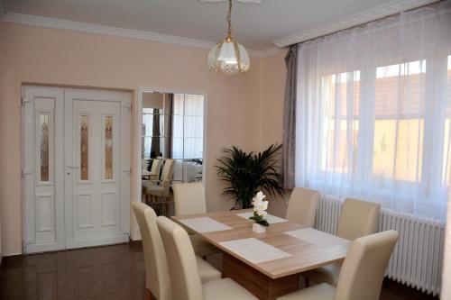 une salle à manger avec une table en bois et des chaises blanches dans l'établissement Molnár Vendégház, à Újfehértó