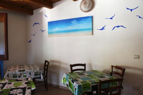 ein Esszimmer mit zwei Tischen und Vögeln an der Wand in der Unterkunft B&B da Gio' in Santa Maria la Palma