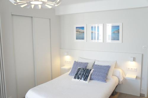 a white bedroom with a bed with blue and white pillows at T1 Moderne Plage des Catalans in Marseille