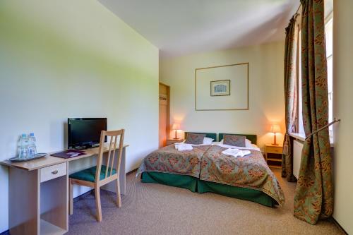 a bedroom with a bed and a desk and a computer at Biały Pałac Palczew in Palczew