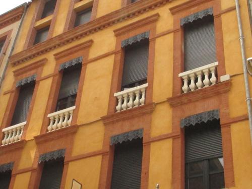 an orange building with windows and blinds at Hôtel le Pastel in Toulouse