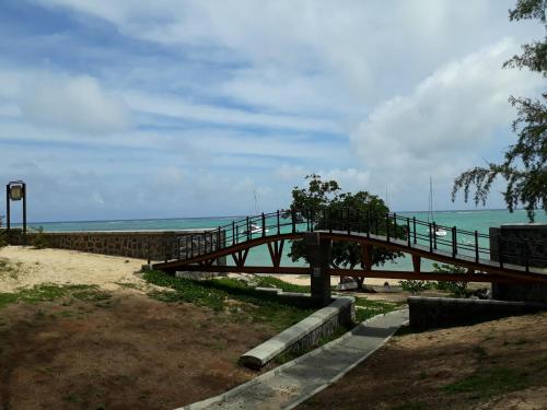 a wooden bridge over a beach with the ocean at Allamanda Apartments - 100m Bain Boeuf Beach in Bain Boeuf