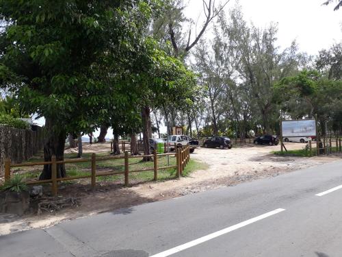 a road with a fence and cars parked next to a tree at Allamanda Apartments - 100m Bain Boeuf Beach in Bain Boeuf