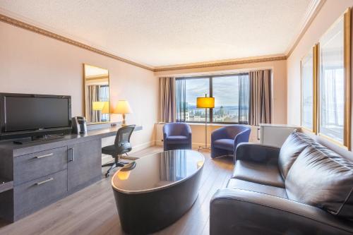 a living room with a couch and a tv at Hôtel Le Concorde Québec in Quebec City