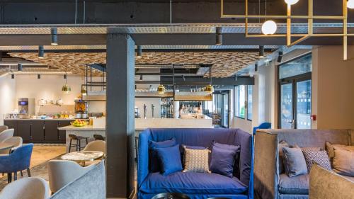 a living room with blue chairs and a bar at ibis Styles Laval Centre Gare in Laval