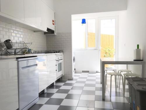 a kitchen with white cabinets and a checkered floor at Lemon Tree Apartments in Faro